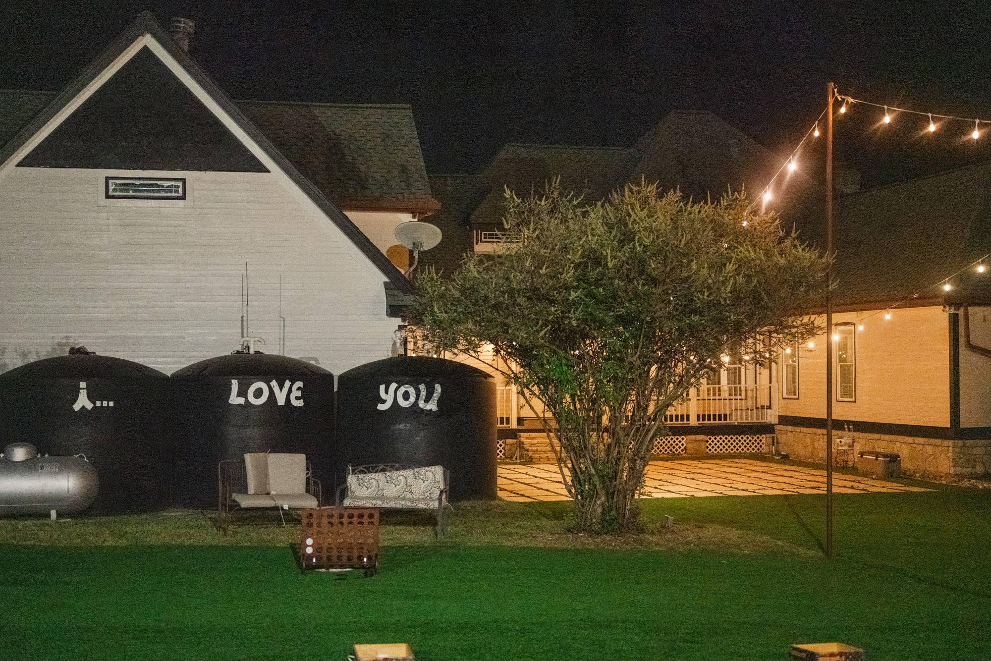 The white barn and the ranch house lit up at night