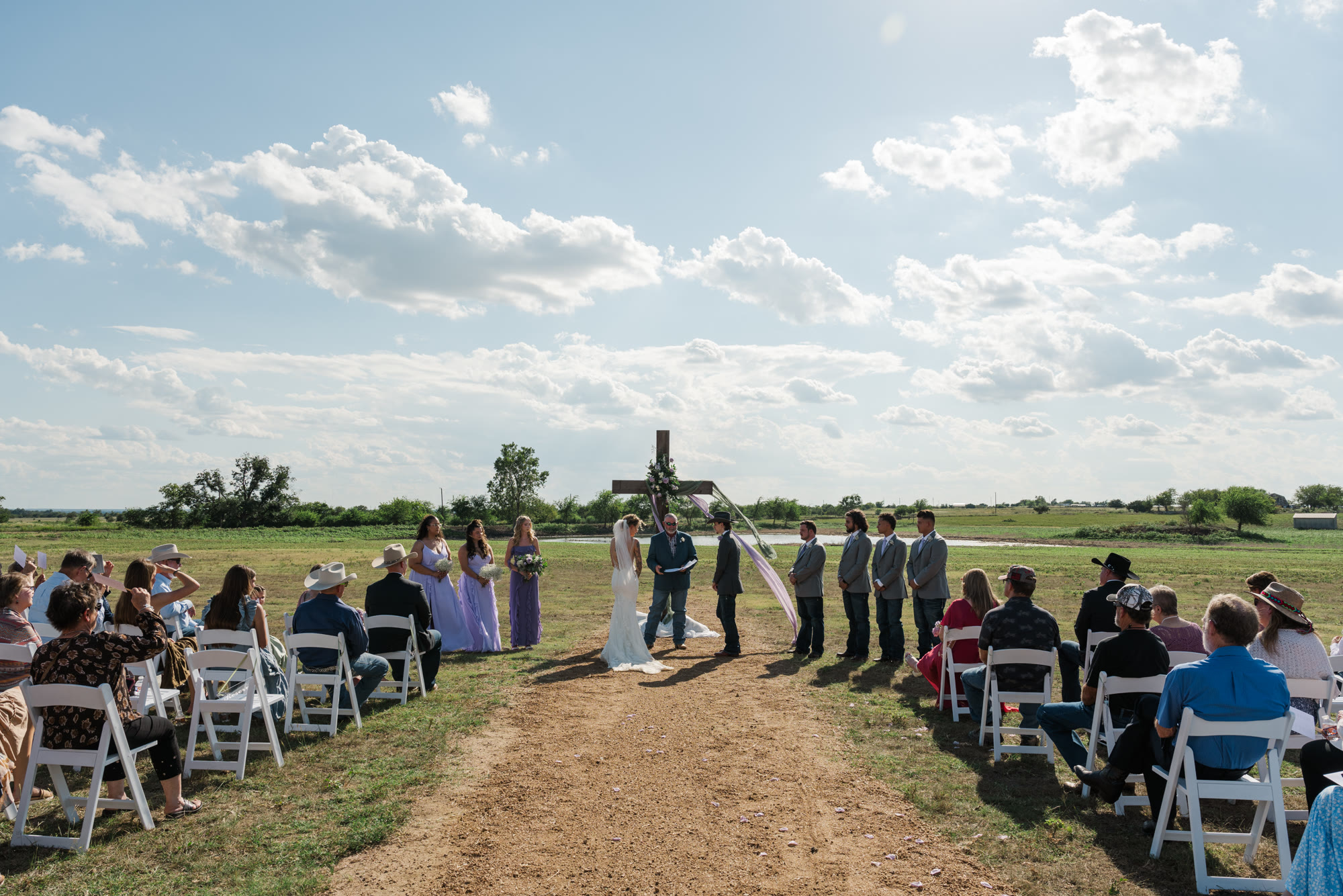 Guests seated along the aisle for an open-field ceremony at the cross